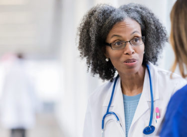 Female doctor speaks with colleague.