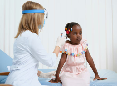 Little girl sitting on bed during medical consultation.