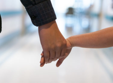 Father holding daughter's hand in hospital